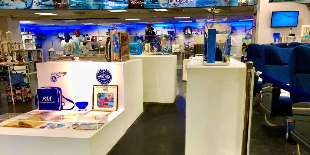 The First Flight Out Pan Am exhibit at CocoWalk: display cases of Pan Am artifacts, a history wall overhead and vintage airline seats